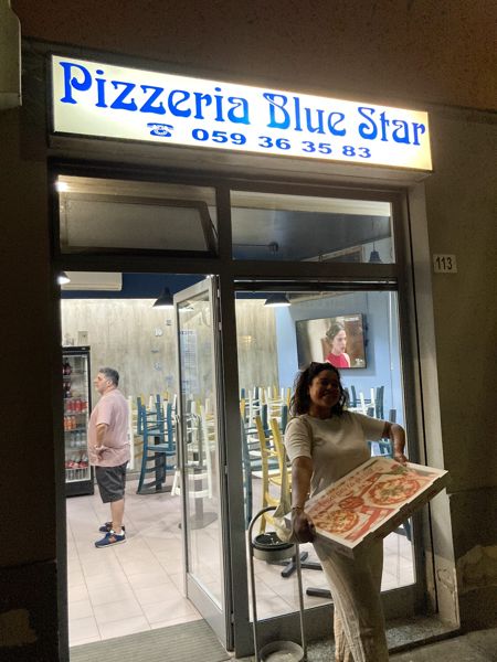 L'insegna blu della Pizzeria Blue Star, la sera